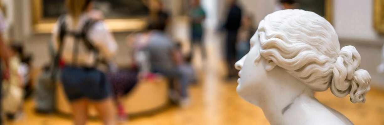 Au premier plan à droite, tête d'une statue de femme en marbre, le reste est flou mais on distingue du public au MAH