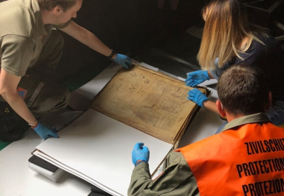 3 personnes civilistes en train de consulter un livre ancien pour vérifier les dommage issus d'un sinistre