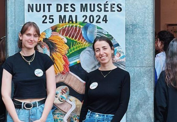 Deux jeunes filles souriantes devant l'affiche de la Nuit des musées 2024