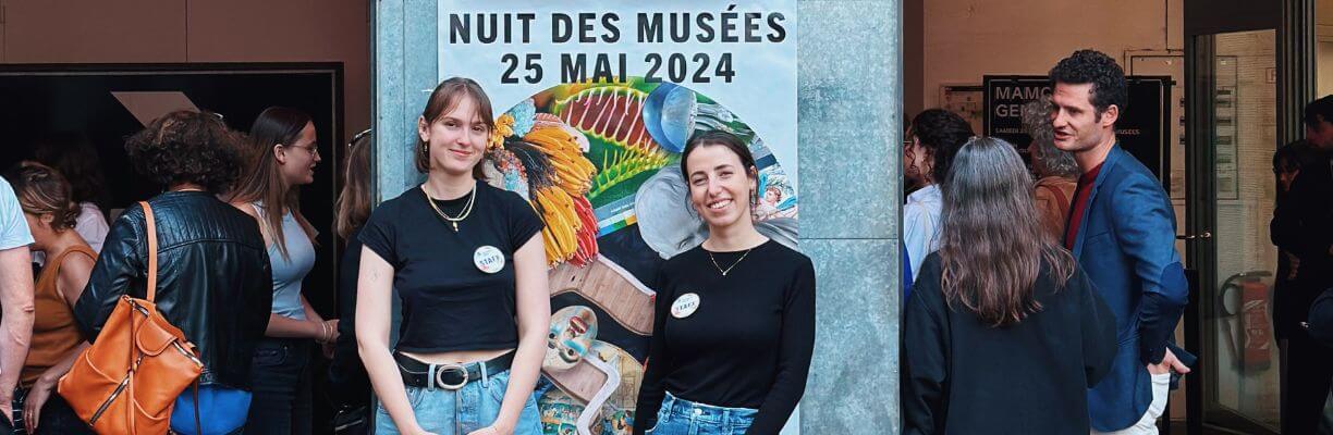 deux personnes souriantes devant l'affiche de la nuit des musées 2024 devant le mamco entourée d'autres visiteurs