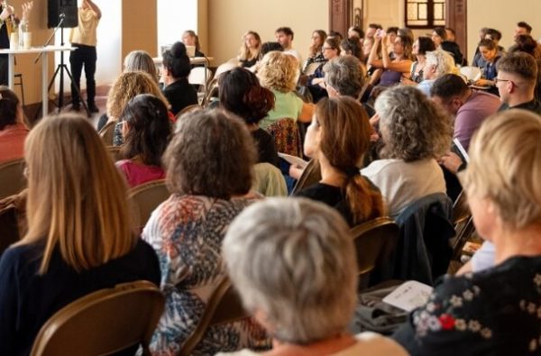 Soixantaine de personnes assises pour écouter un orateur dans la salle des armures du MAH