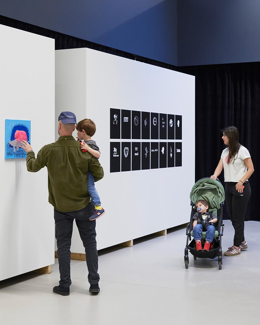 Visiteurs et visiteuses devant des œuvres du FMAC sur des murs blancs