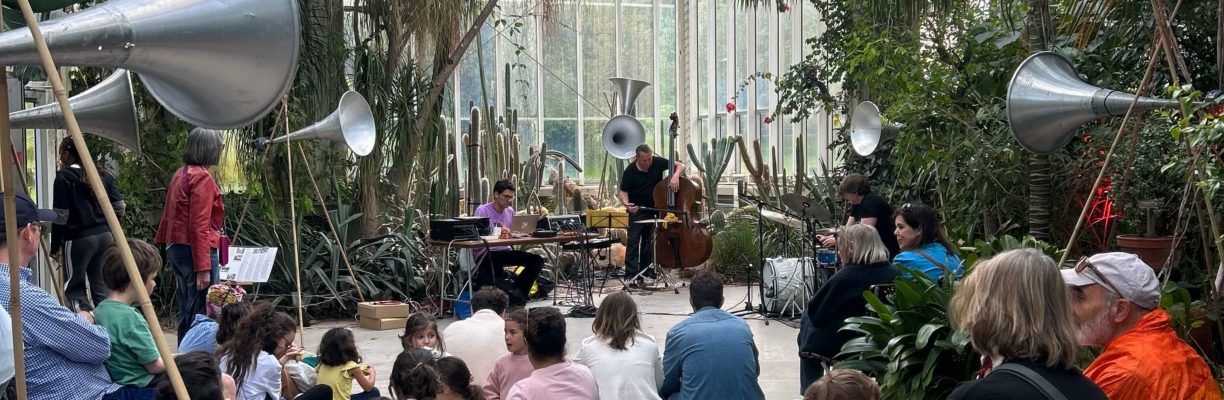 Public assis de dos dans une serre du Jardin botanique de Genève écoutant un concert lors de la Nuit des musées 2025