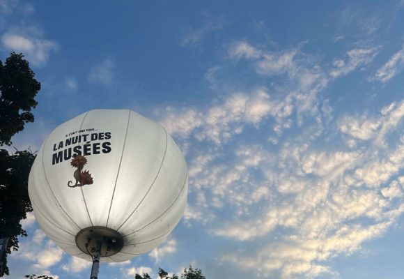 Ballon lumineux de la Nuit des musées 2025 qui se distingue sur un ciel bleu avec quelques nuages.