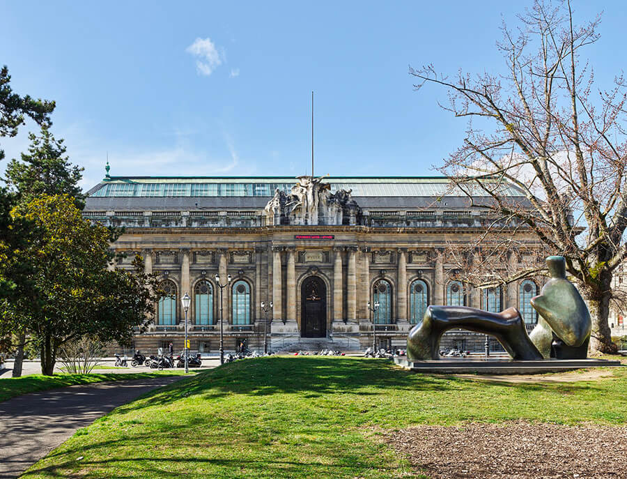 Statue, arbres et façade du MAH avec de décompte du temps, ciel bleu