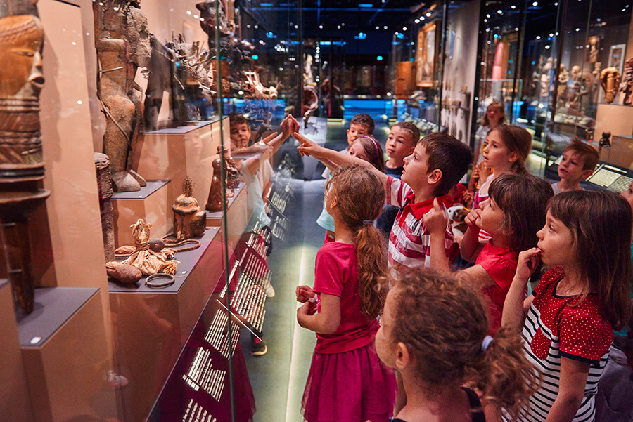 Jeune public regardant les objets d'une vitrine d'exposition au MEG