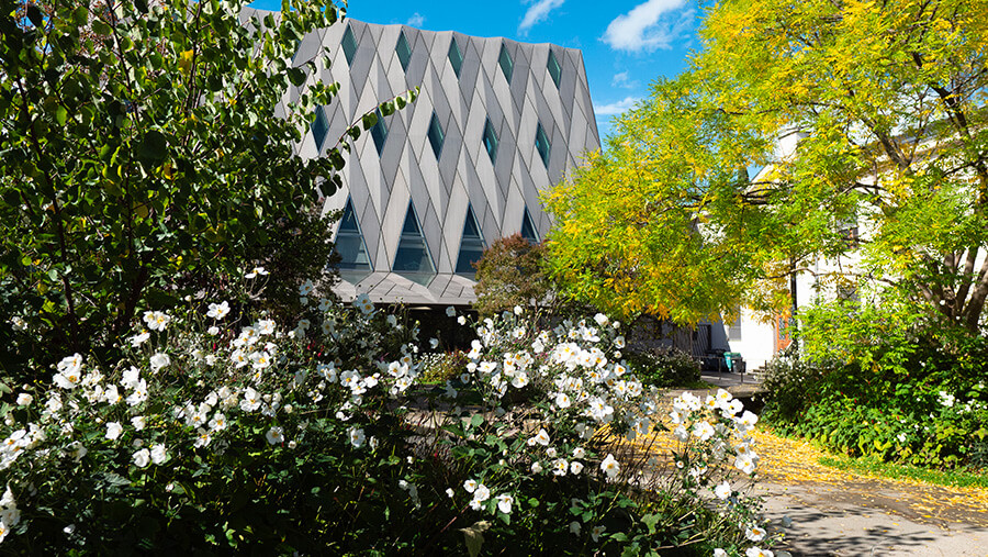 Façade du MEG avec des arbres et buissons en fleurs