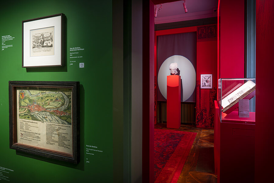 Deux tableaux accrochés sur un mur vert à gauche et le buste d'une statue sur un socle rouge à droite au Musée de la Réforme