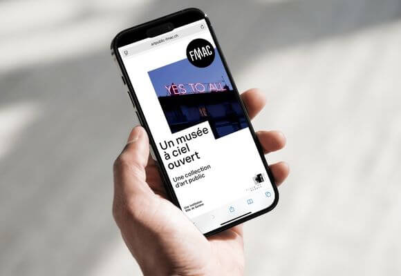 main tenant un téléphone portable avec l'application "un musée à ciel ouvert" visible