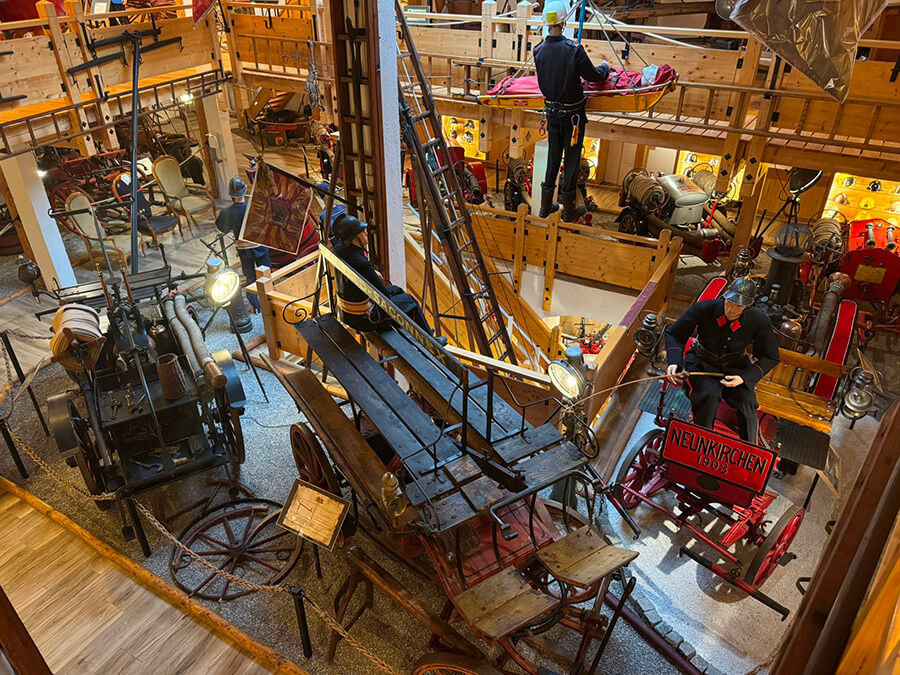 Vue depuis le balcon sur des anciens véhicules de pompiers, échelles, mannequin en uniforme au Musée des Sapeurs-pompiers de Genève