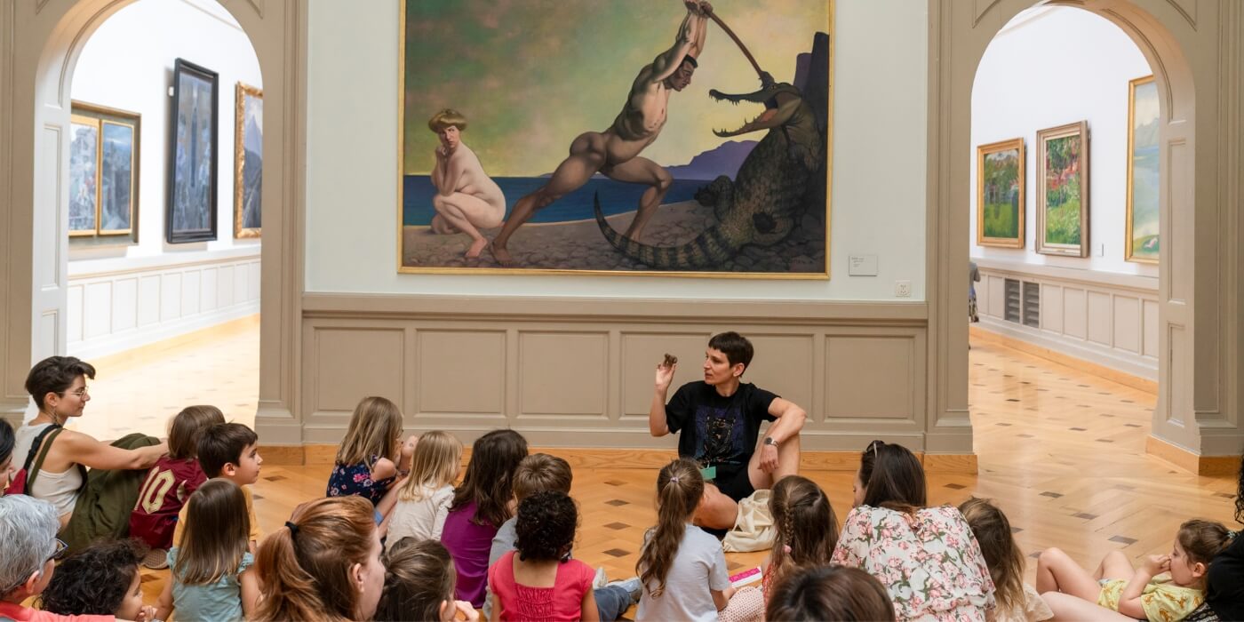 jeune public écoute une guide dans une exposition devant des peintures