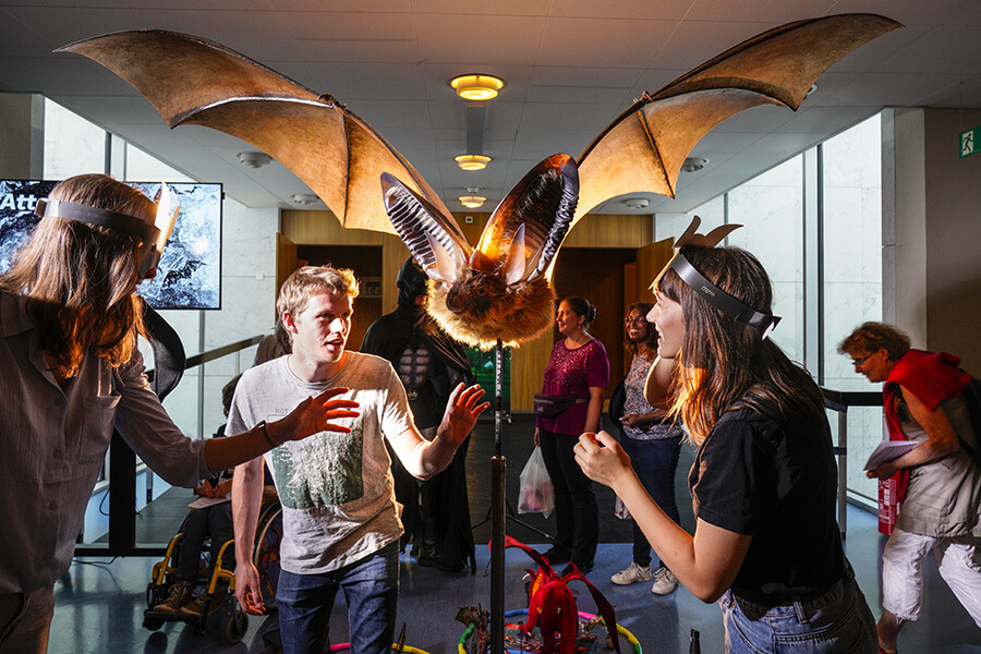 Public adolescent regardant une énorme chauve-souris empaillée avec ses ailes écartées