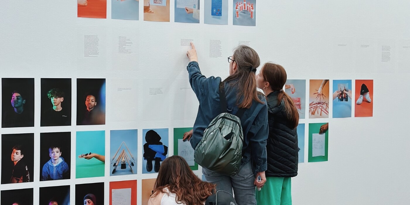 3 personnes observant des photographies sur un mur d'exposition