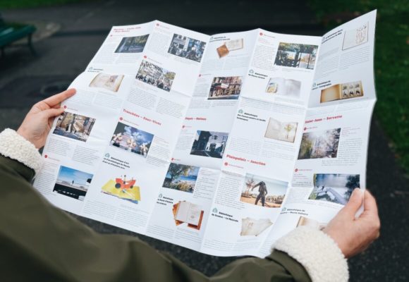 hands holding a leaflet of cultural trails with images of works and the neighbourhood in which they are located