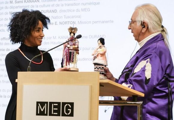 Carine Durant échangeant une poupée avec un homme âgé aux cheveux longs et blancs