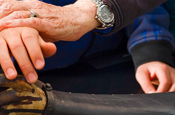 Zoom sur une main âgée sur une main plus jeune qui touche une sculpture