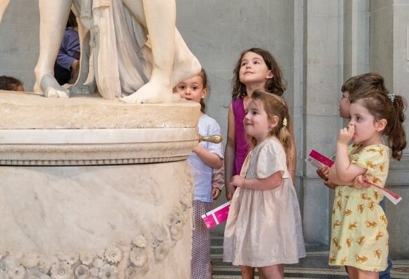 Junges Publikum am Fuße einer Statue auf einem Sockel