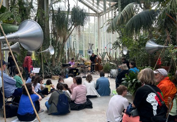 Public assis de dos dans une serre du Jardin botanique de Genève écoutant un concert lors de la Nuit des musées 2025