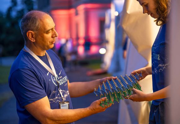 Médiateur de la Nuit de la Science expliquant une maquette à une jeune fille en face de lui