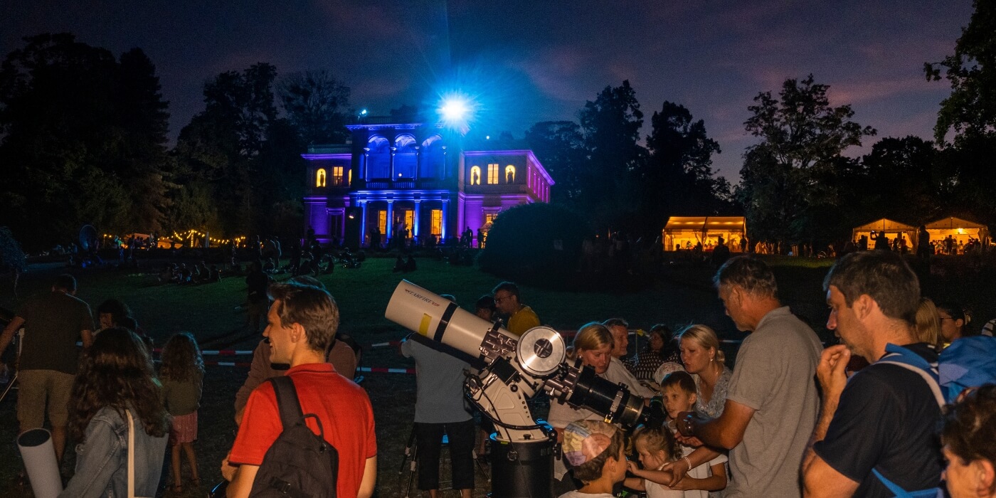 groupe de personnes regardant au télescope dans le parc de la perle du lac devant le musée d'histoire des science de nuit